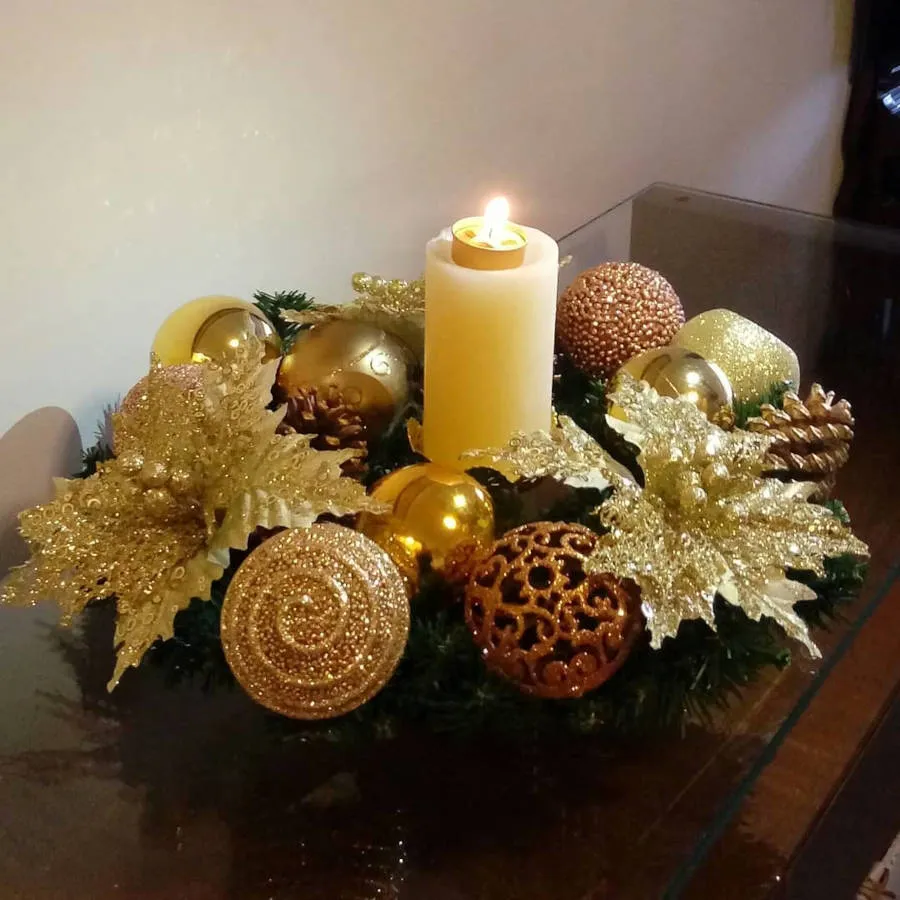 Decoração natalina dourada com vela no meio.