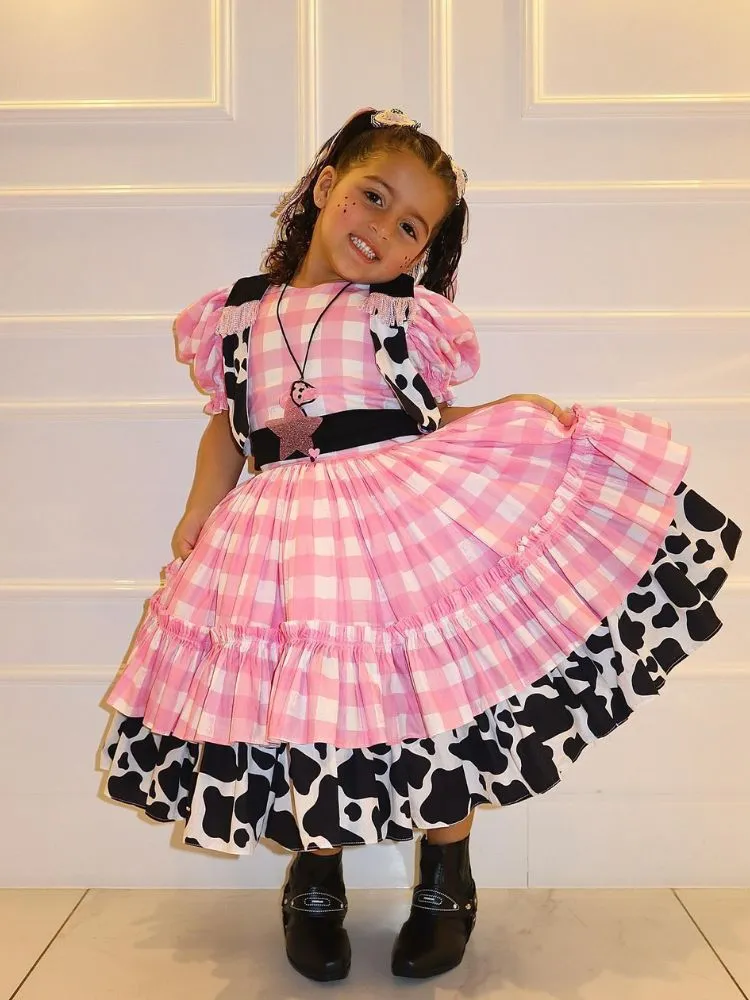 Menina de pele clara com vestido xadrez rosa com detalhes cow print 