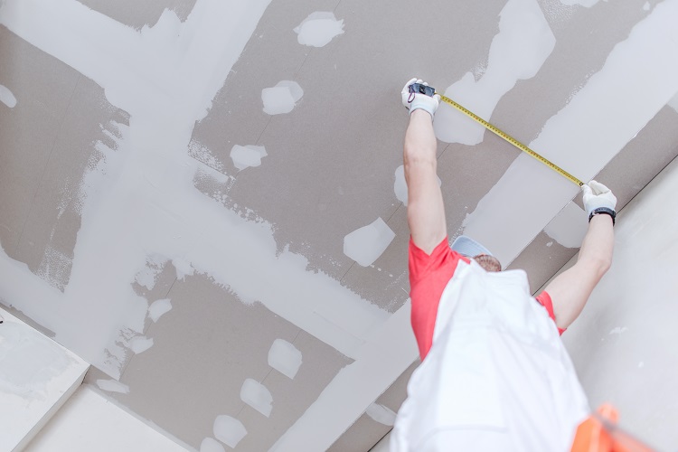 homem medindo forro de drywall