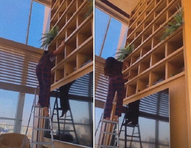 Dia de faxina com Sabrina Sato. Na imagem é possível ver a apresentadora em cima de uma escada limpando a estante da sala Dia de faxina com Sabrina Sato