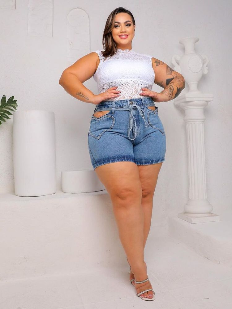 Mulher de pele clara usando body branco e shorts jeans