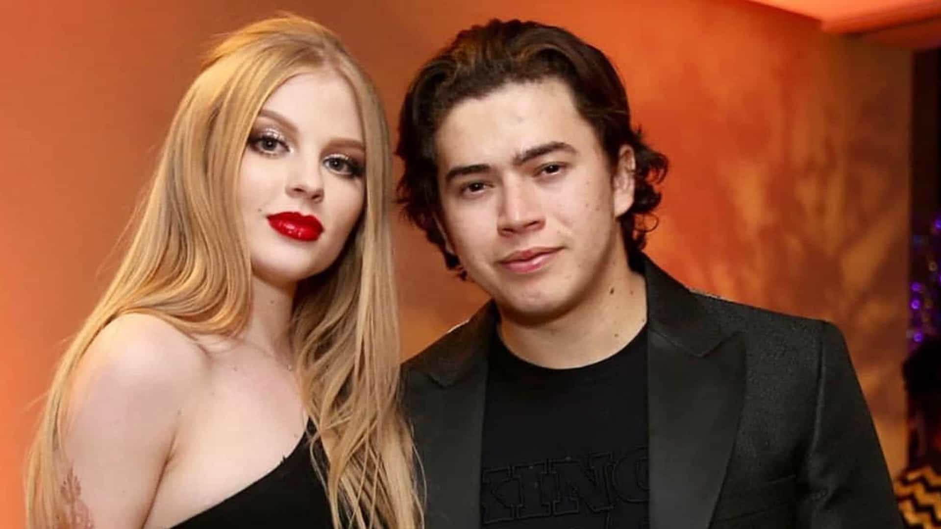 Whindersson Nunes e a ex-mulher Luísa Sonza posam para fotógrafos. Ela com batom vermelho e vestido preto de um ombro só, ele com blazer e camiseta preta ao fundo backdrop laranja Whindersson Nunes sobe em jatinho de 1,4 milhão 4