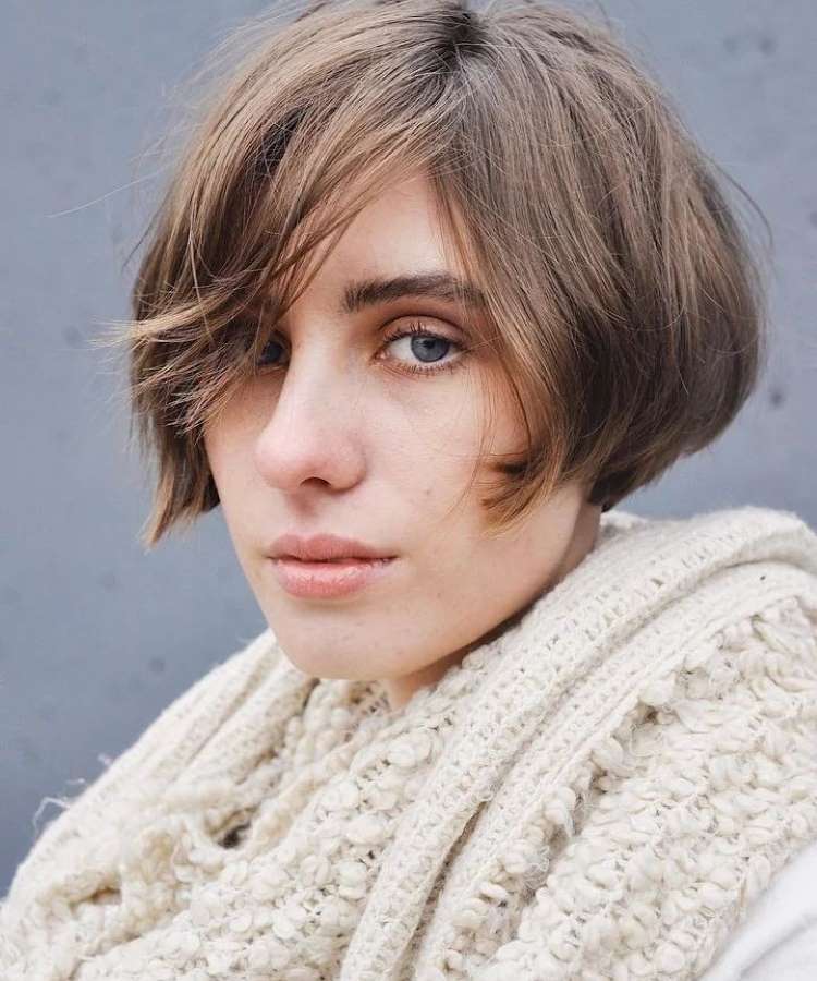 Mulher com cabelo liso castanho-claro curto e repicado próximo à orelha