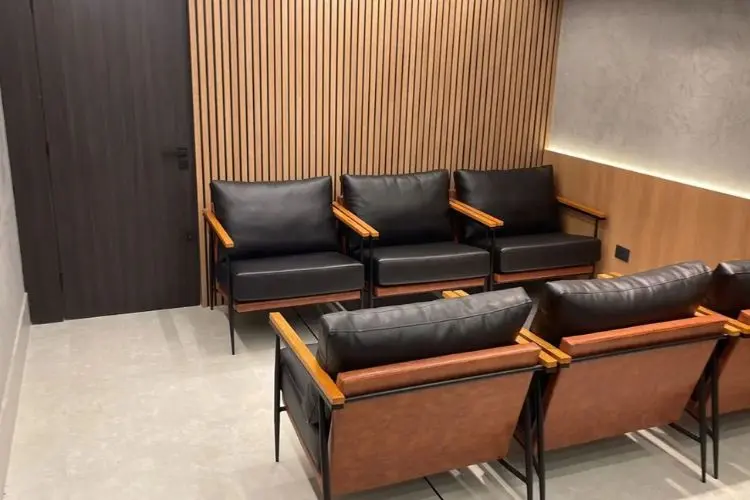 Sala com madeira e poltronas pretas em couro natural e detalhes em marrom