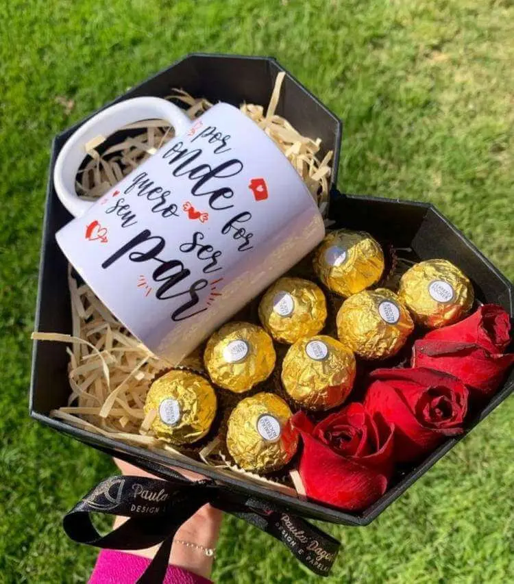 Cesta preta em formato de coração com bombons, caneca e flores