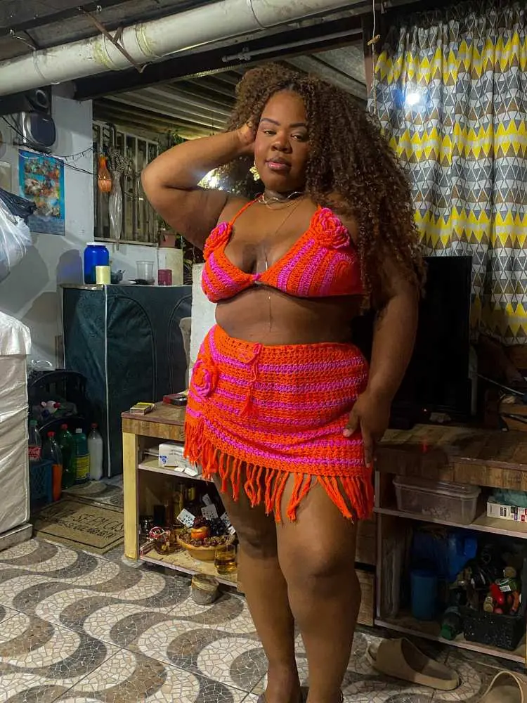 Mulher de pele negra com conjunto de crochê em laranja e rosa 