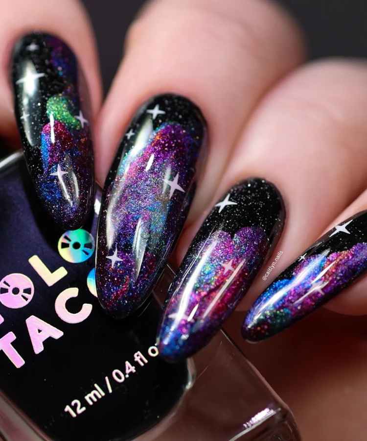 Pessoa de pele clara com unha almond comprida e nail art de galáxia com esmalte magnético