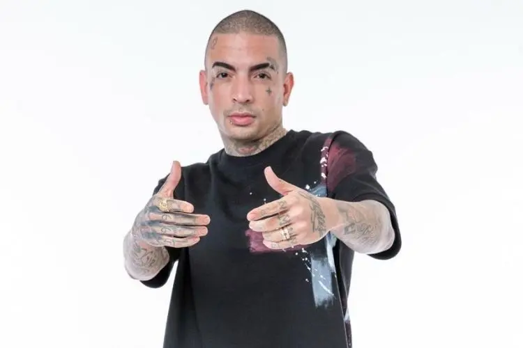 MC Guimê usando blusa preta com detalhes em bordô e azul