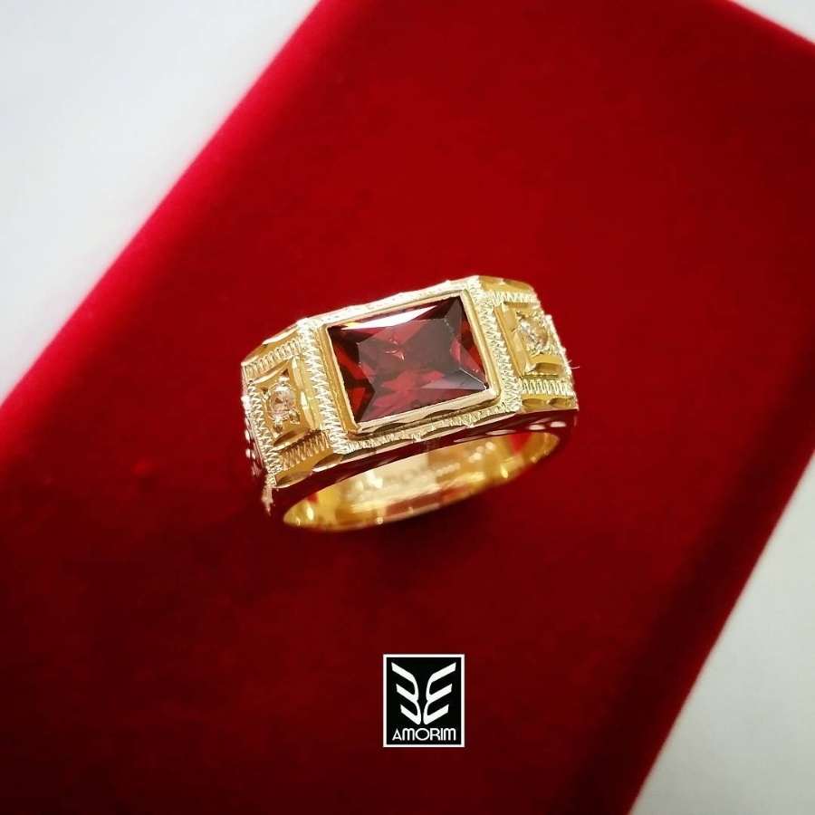 Anel dourado com pedra vermelha sobre caixa vermelha
