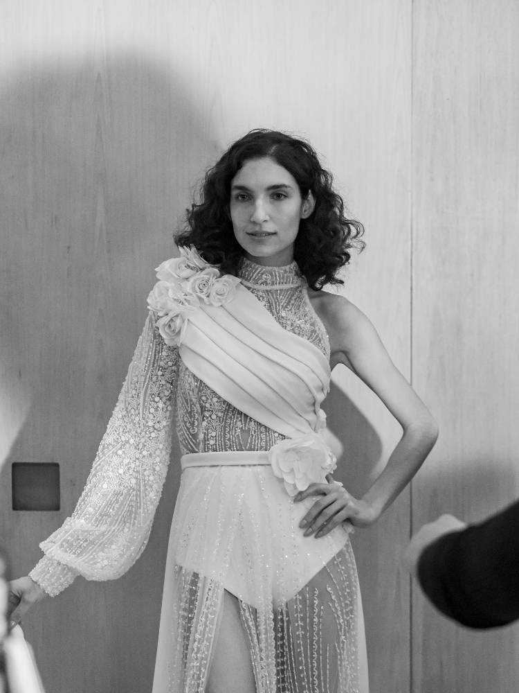 Foto em preto e branco de mulher usando vestido de noiva com ombro só, manga comprida, hot pant e transparência