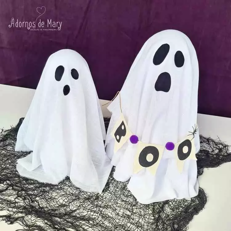 Dois fantasmas de pano branco com olhos e bocas pretos, um deles com faixa escrito "boo", ambos sobre rede preta