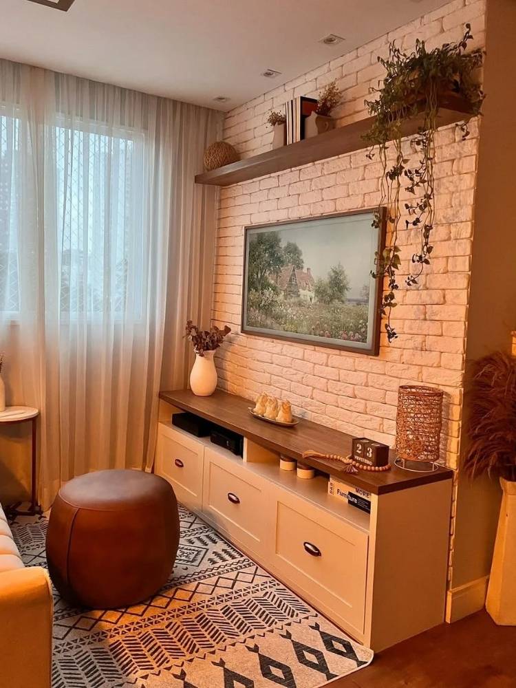 Parede de tijolos de sala de TV com decorações terrosas sendo iluminada por luz amarela 