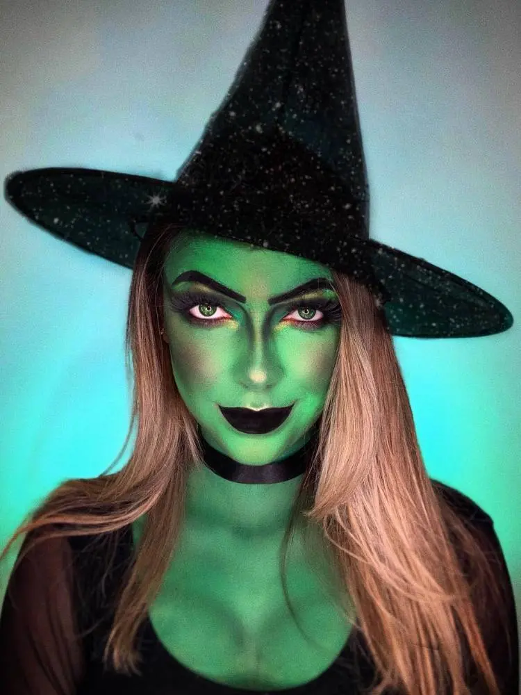 Mulher fantasiada de bruxa com corpo pintado de verde e batom preto
