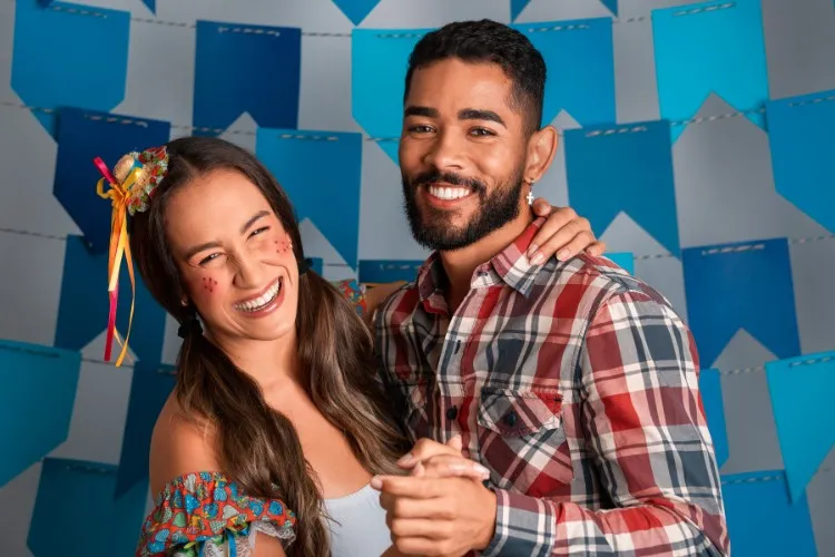 Mulher com trajes juninos dançando com homem de pele negra usando camisa xadrez 