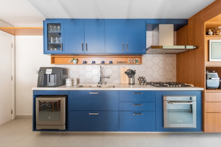 Cozinha com móveis azul e em madeira, moderna, com azulejos claros hexagonais