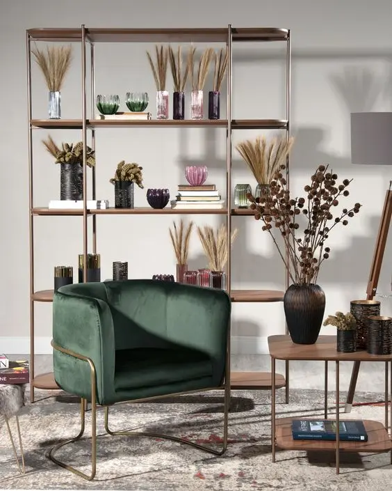 Hall com estante vazada decorada, tapete bege, poltrona verde e mesa de madeira