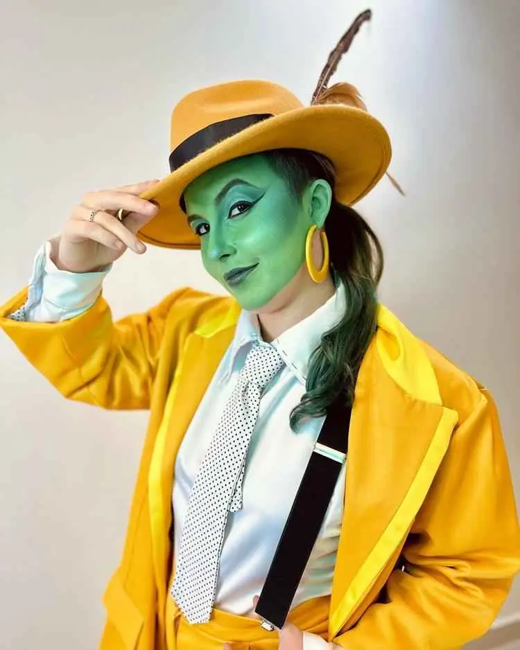 Mulher de pele clara fantasiada de Máscara, com pele verde e delineado