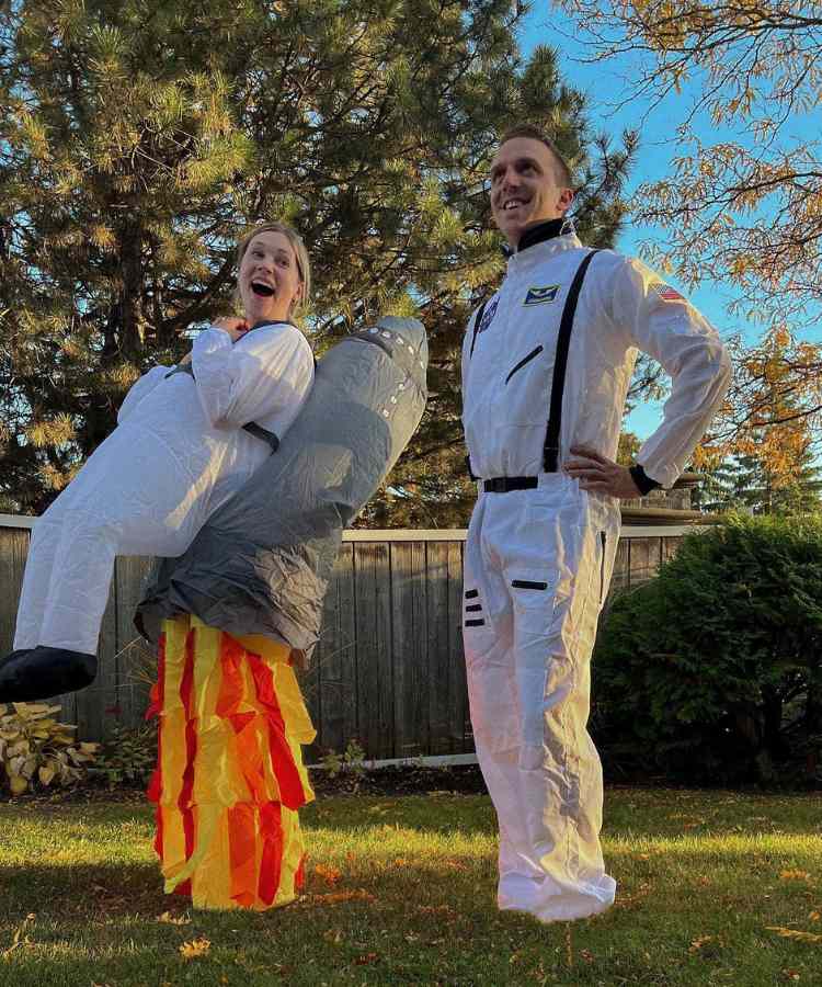 Traje de Dia das Bruxas para namorados: Astronautas. Ele usa macacão branco e ela roupa inflável com macacão branco e foguete