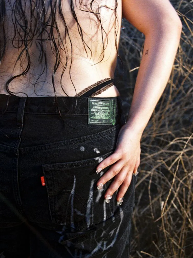 Um close-up na claça, uma calça preta com uma estampa cinza e uma etiqueta da Levis
