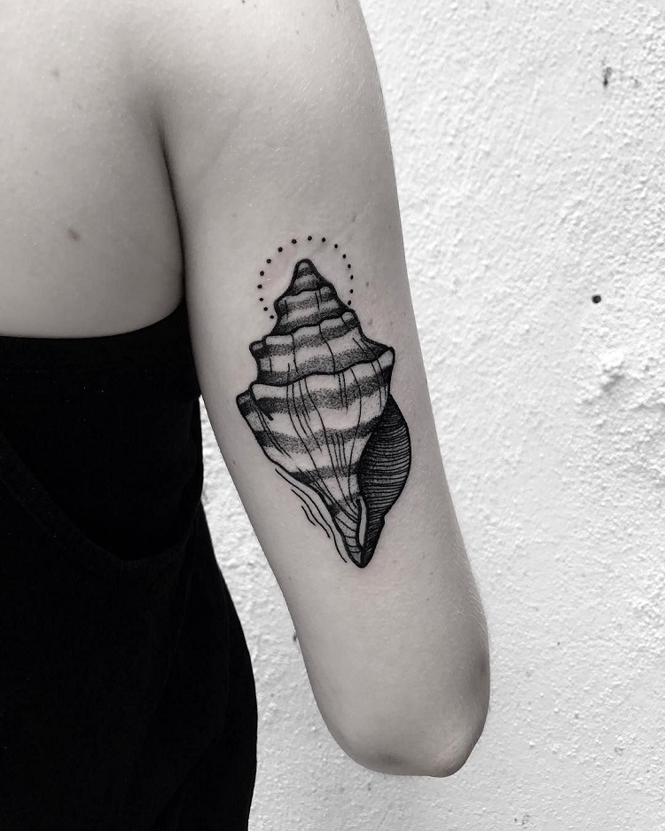 mulher com tatuagem de concha no braço