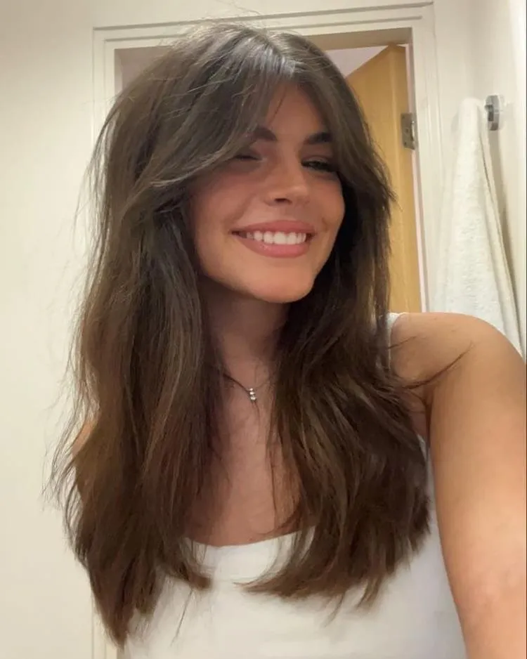 mulher de cabelo médio liso castanho e franja média