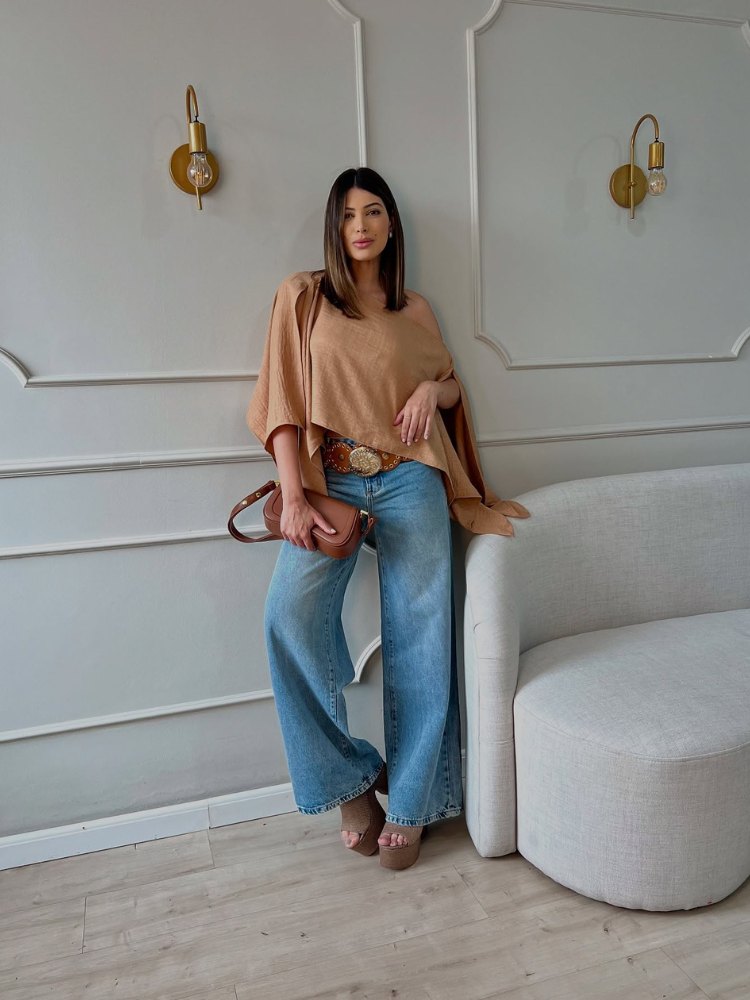 Mulher de pele clara com camisa bege e calça jeans pantalona 