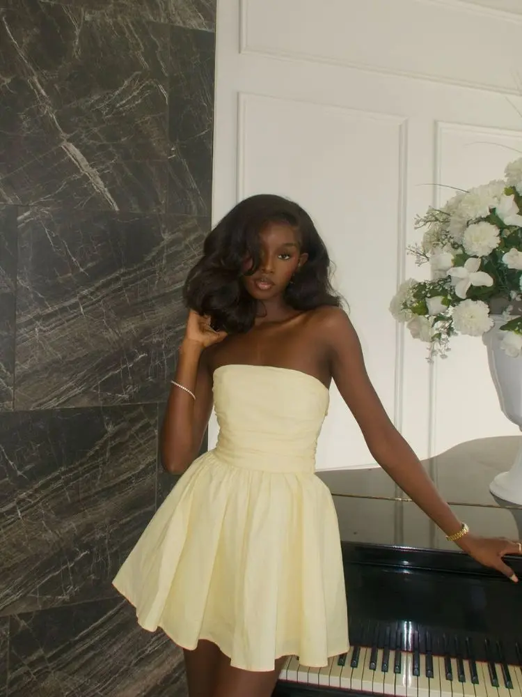 Mulher de pele negra usando vestido curto, sem alças amarelo-manteiga