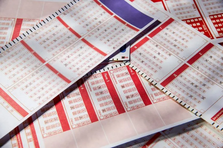 Foto de bilhetes de loteria em branco, vermelho e azul, com alguns números marcados