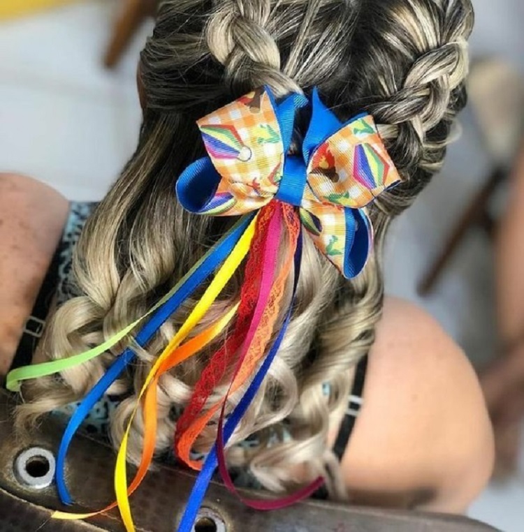 Mulher loira de pele clara com laço colorido no cabelo