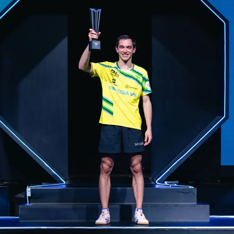 Hugo Calderano usando camiseta do Brasil e segurando troféu