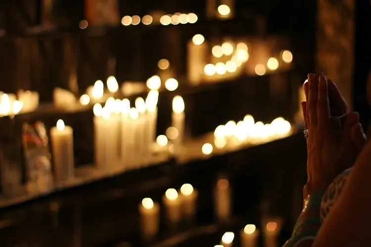 mulher fazendo orações de Ano Novo em frente a velas acesas
