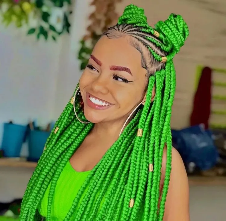 Mulher com trança nagô e box braids verde neon, penteado com dois coques no topo da cabeça.