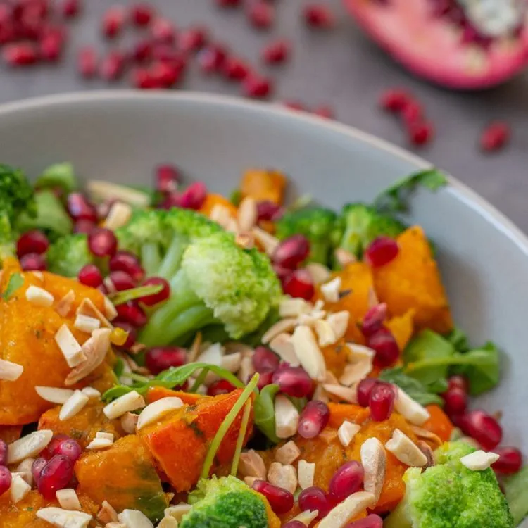 um close em uma salada de abóboras assadas com brócolis e romã