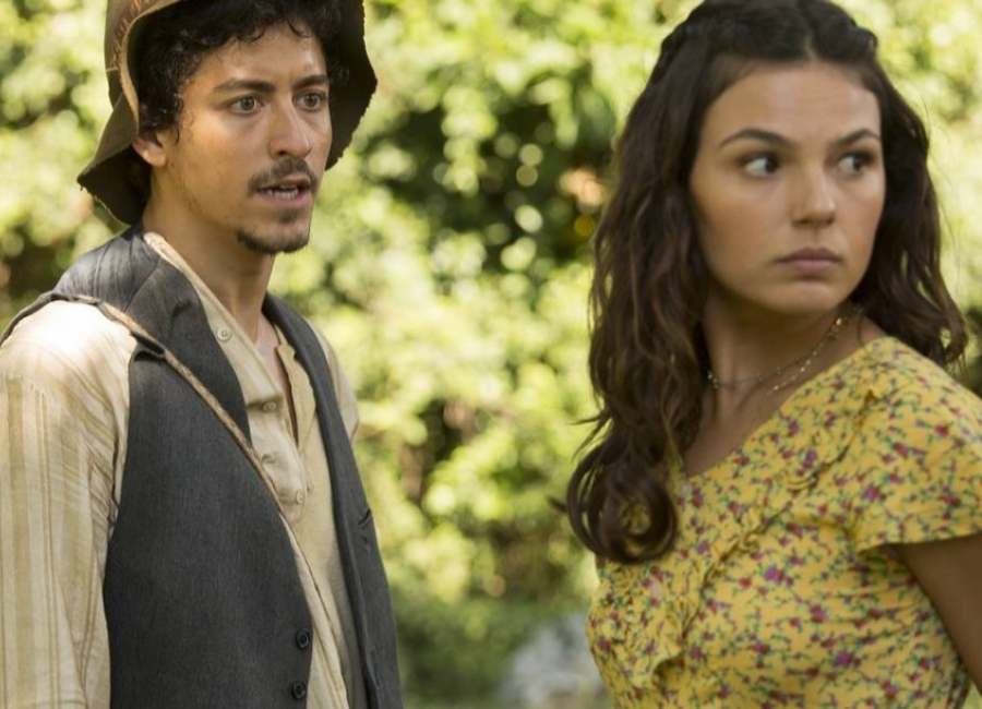 Atores Jesuíta Barbosa e Isis Valverde em cena no filme "Malasartes e o Duelo com a Morte". Ambos estão com cara de surpresa. Ao fundo, plantação embaçada.