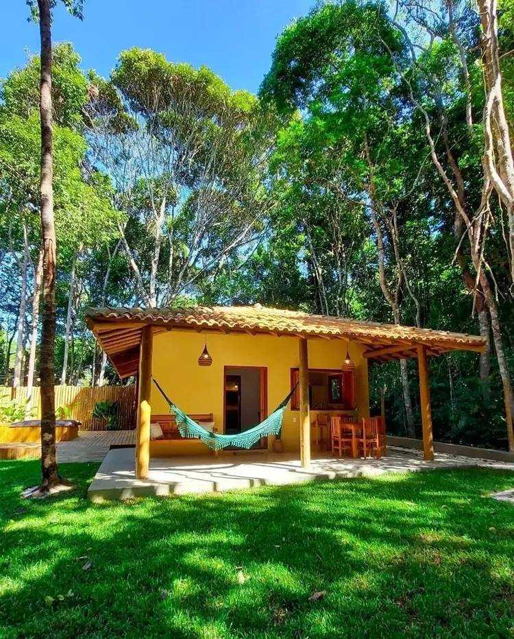 entrada de lar amarela com rede na varanda ao redor de árvores