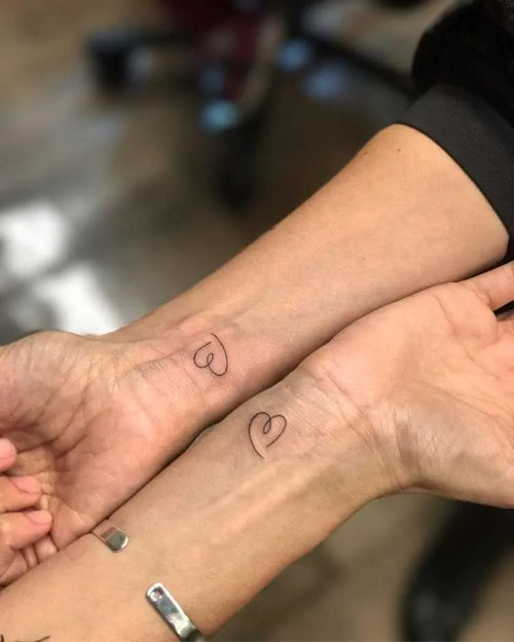 dois braços com tatuagem de coração