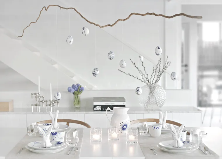 Mesa posta em branco com ovos de Páscoa pendurados 