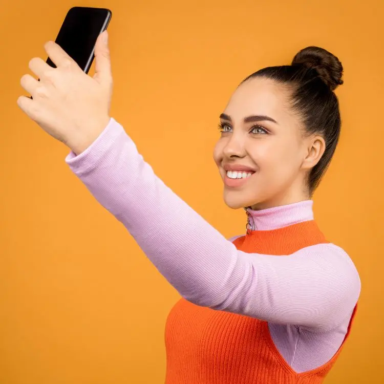 mulher tirando selfie em fundo amarelo