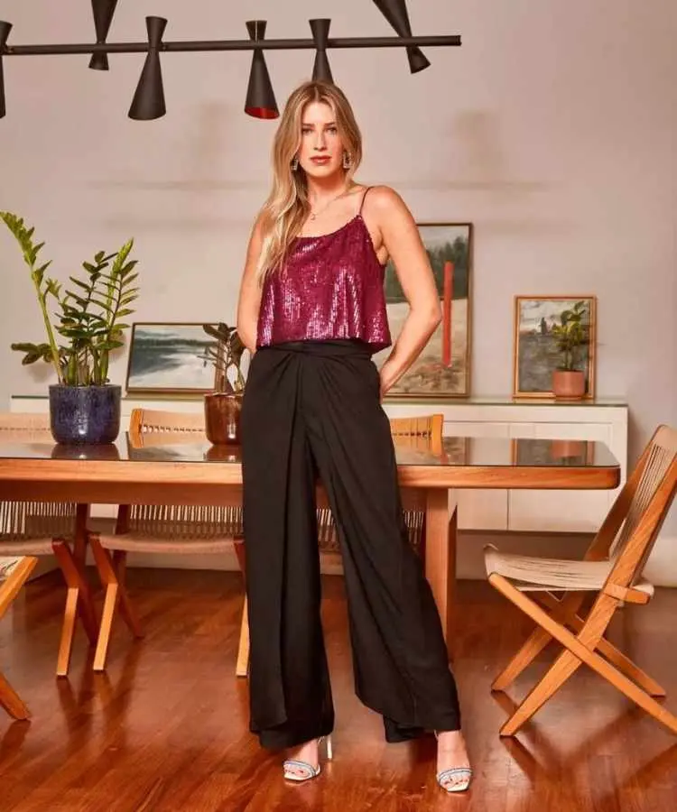Mulher com top vinho brilhoso e caiça pantalona preta