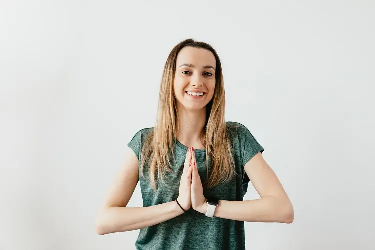 mulher sorrindo com as palmas das mãos unidas