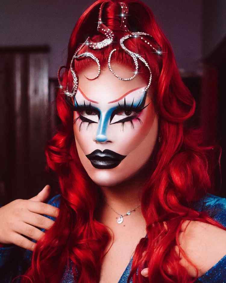 maquiagem drag queen em tons de azul, branco e preto, além de peruca vermelha
