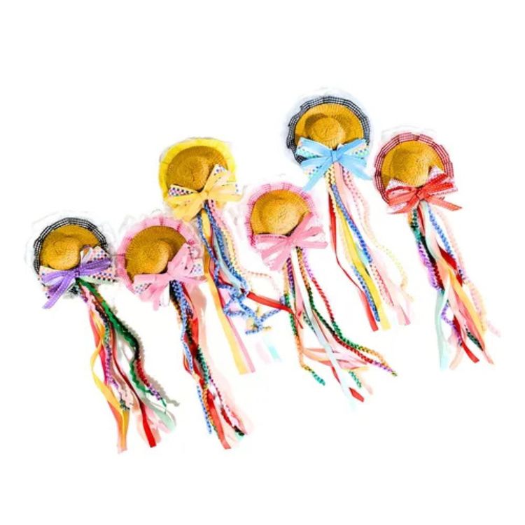 Seis presilhas de cabelo em formato de mini chapéu de festa junina de palha, cada uma decorada com laços coloridos e longas fitas vibrantes de diversas cores, ideais para adornar penteados.