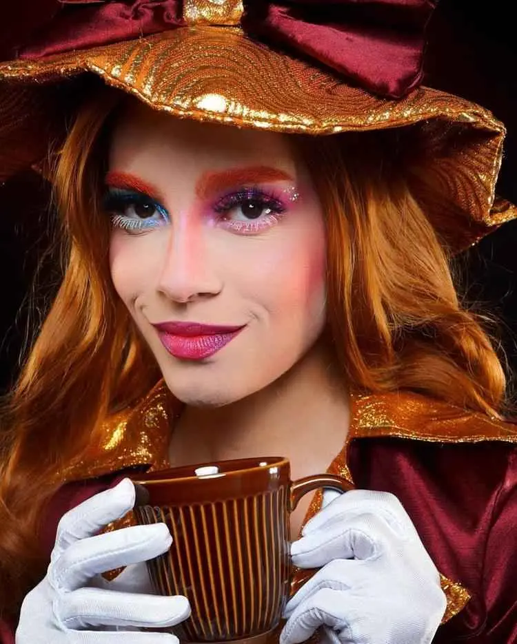Mulher ruiva fantasiada de chapeleiro maluco, com sombra rosa e azul
