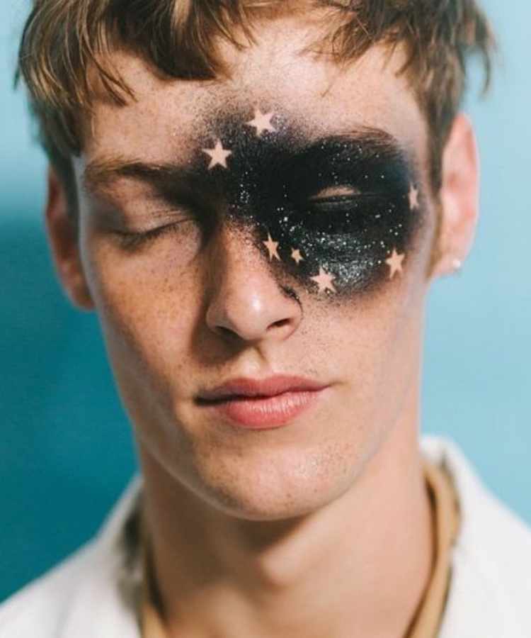Homem com maquiagem preta de glitter com estrelas para o Carnaval.