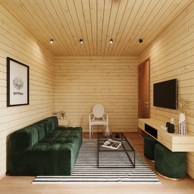 Sala com sofá verde de veludo, tapete claro, mesa preta de centro, cadeira de madeira, quadro branco, puffs verdes e paredes e painel revestidos de pinus, ideia de decoração barata