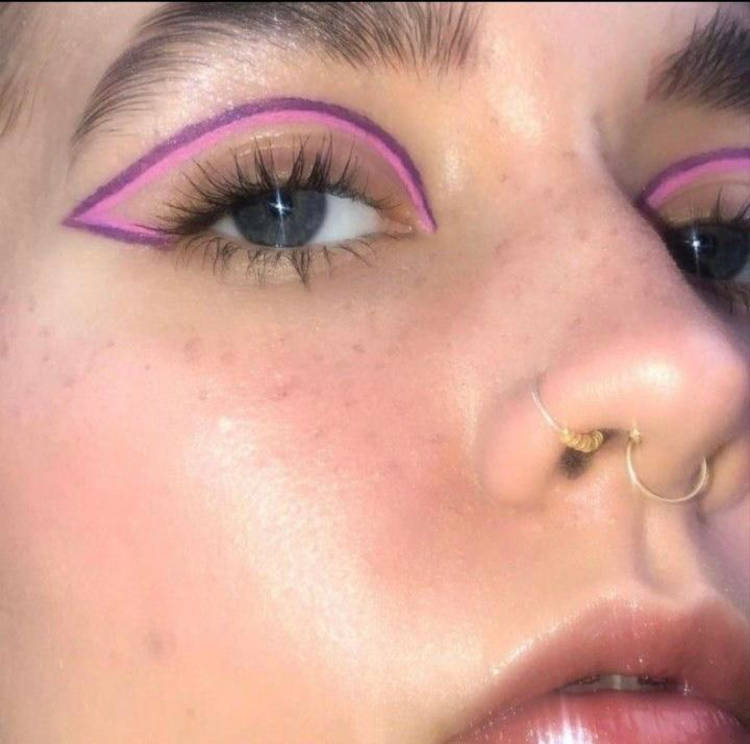 Zoom em mulher de pele clara usando delineado gráfico dulo roxo e rosa 