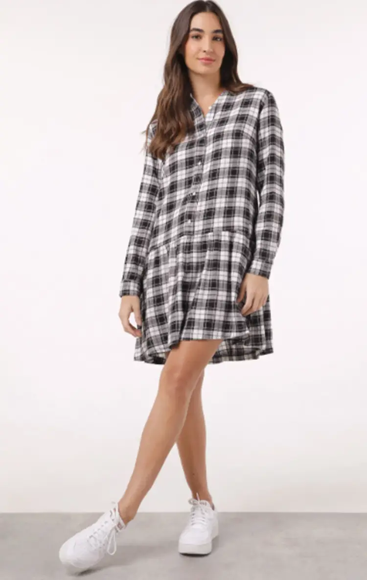 Menina usando vestido xadrez pretoe branco e tênis branco