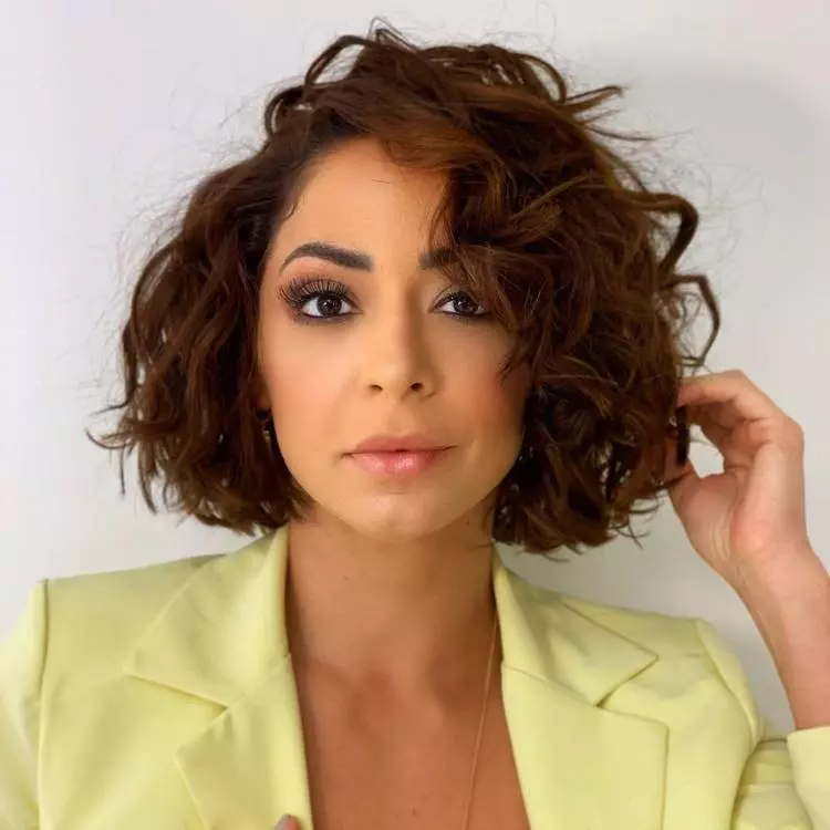 Mulher de pele clara usando blazer amarelo e cabelo chanel ondulado 