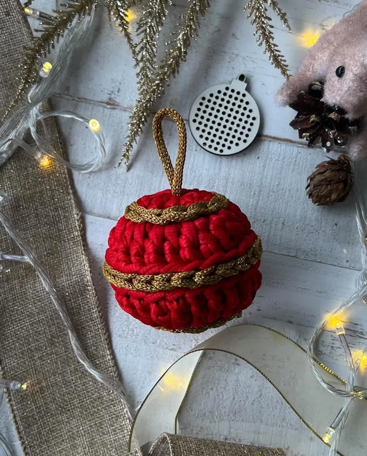 Enfeite bola de Natal vermelho e dourado em mesa com outras decorações natalinas