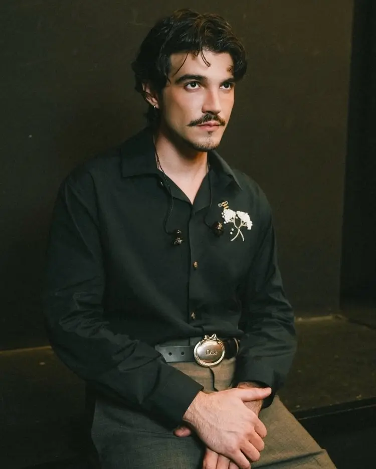 Jão veste camisa e calça preta Dior, com broche de flor branca